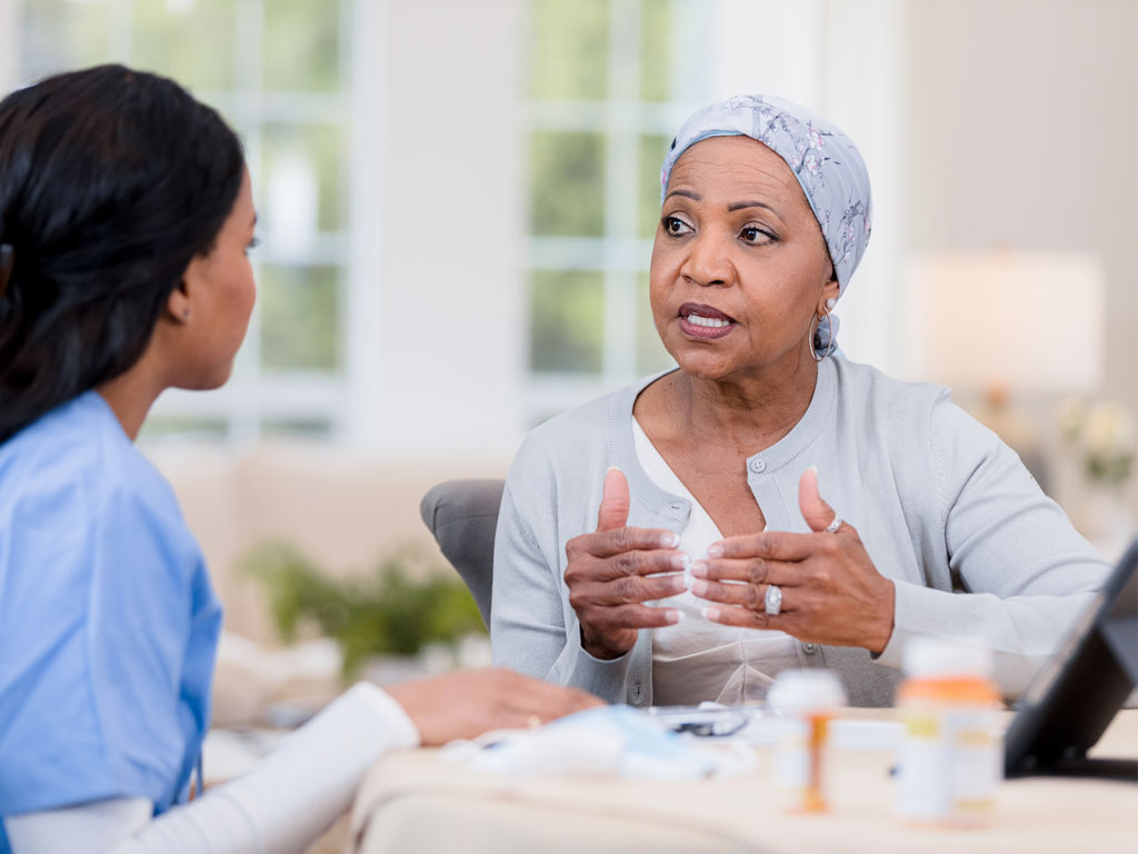 A nurse talks to a cancer patient; ?>