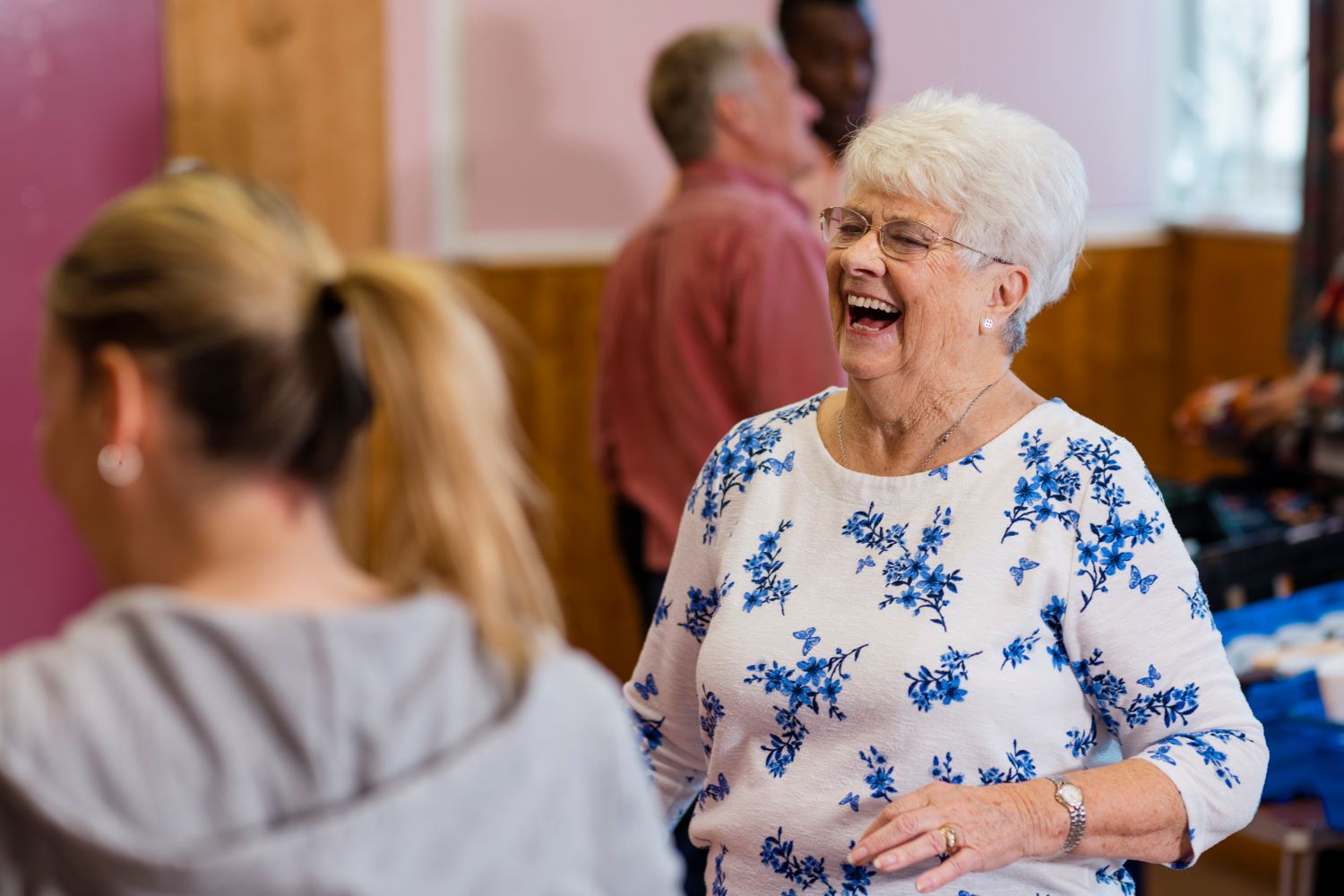 An elderly woman laughing with others at a community group