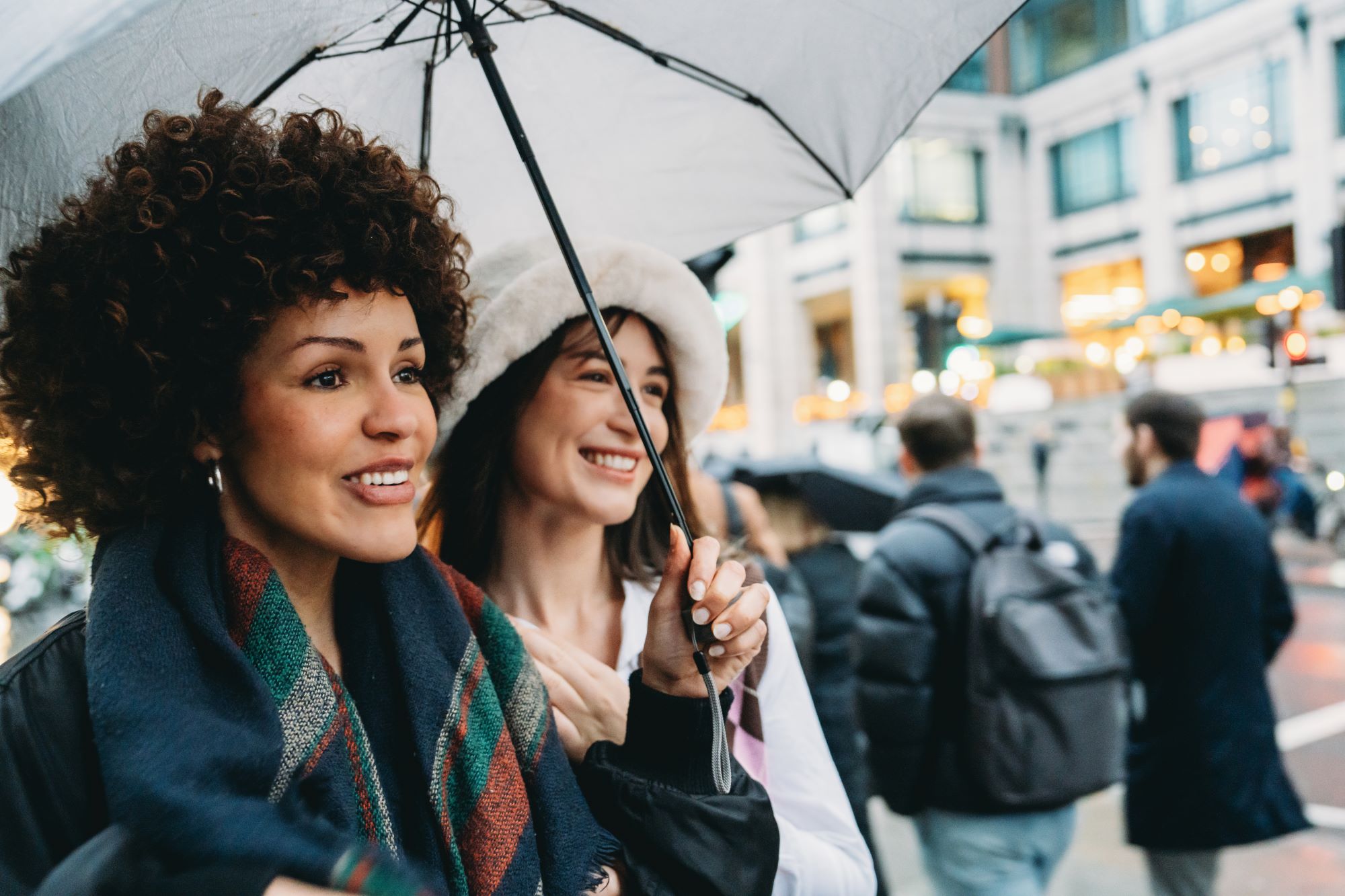 Picture of two women under umbrella smiling; ?>