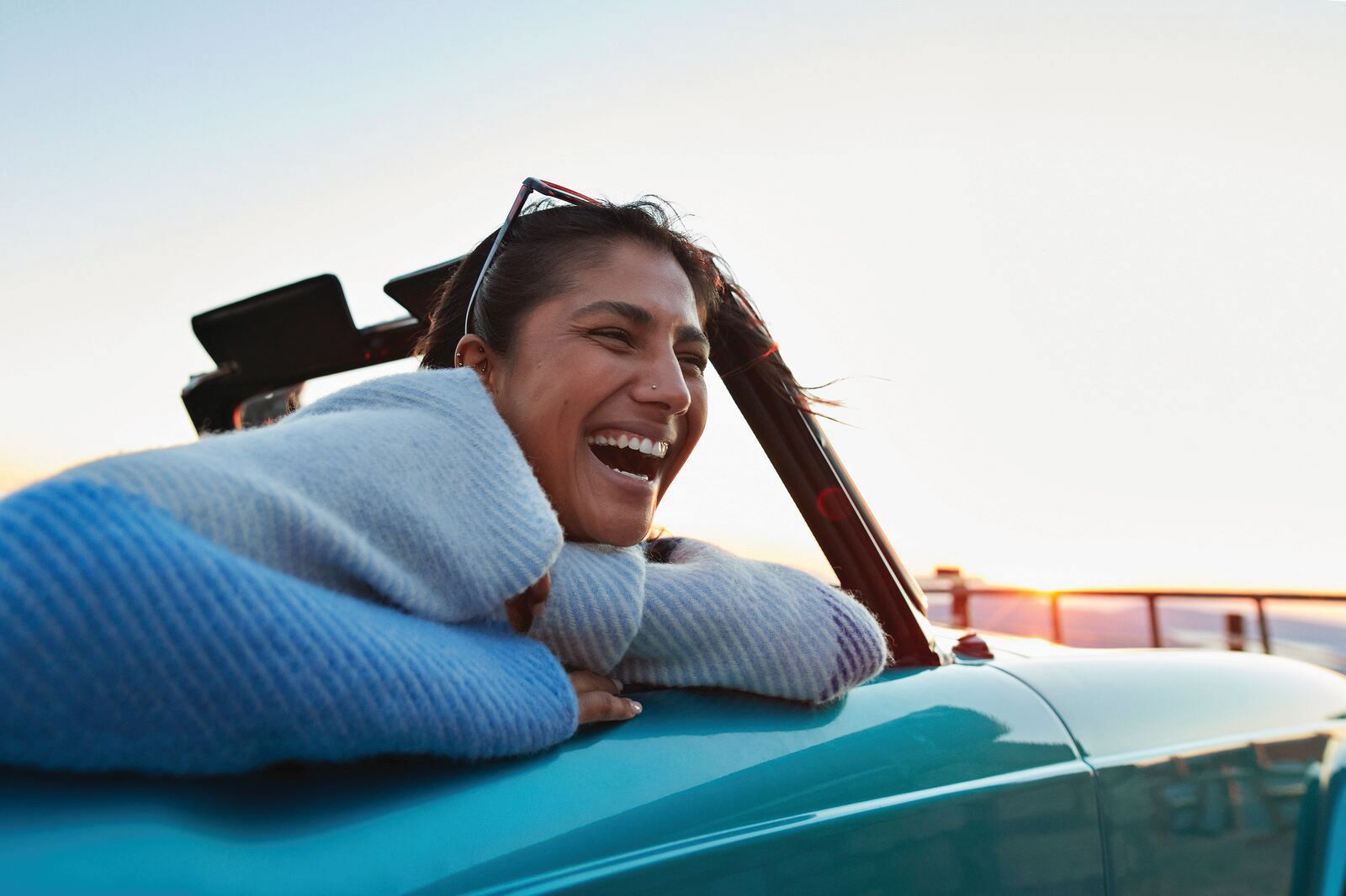 A picture of a woman in a car laughing; ?>