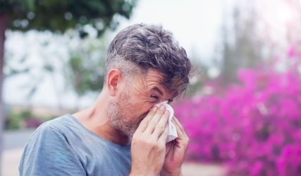 Photo of a man sneezing outdoors