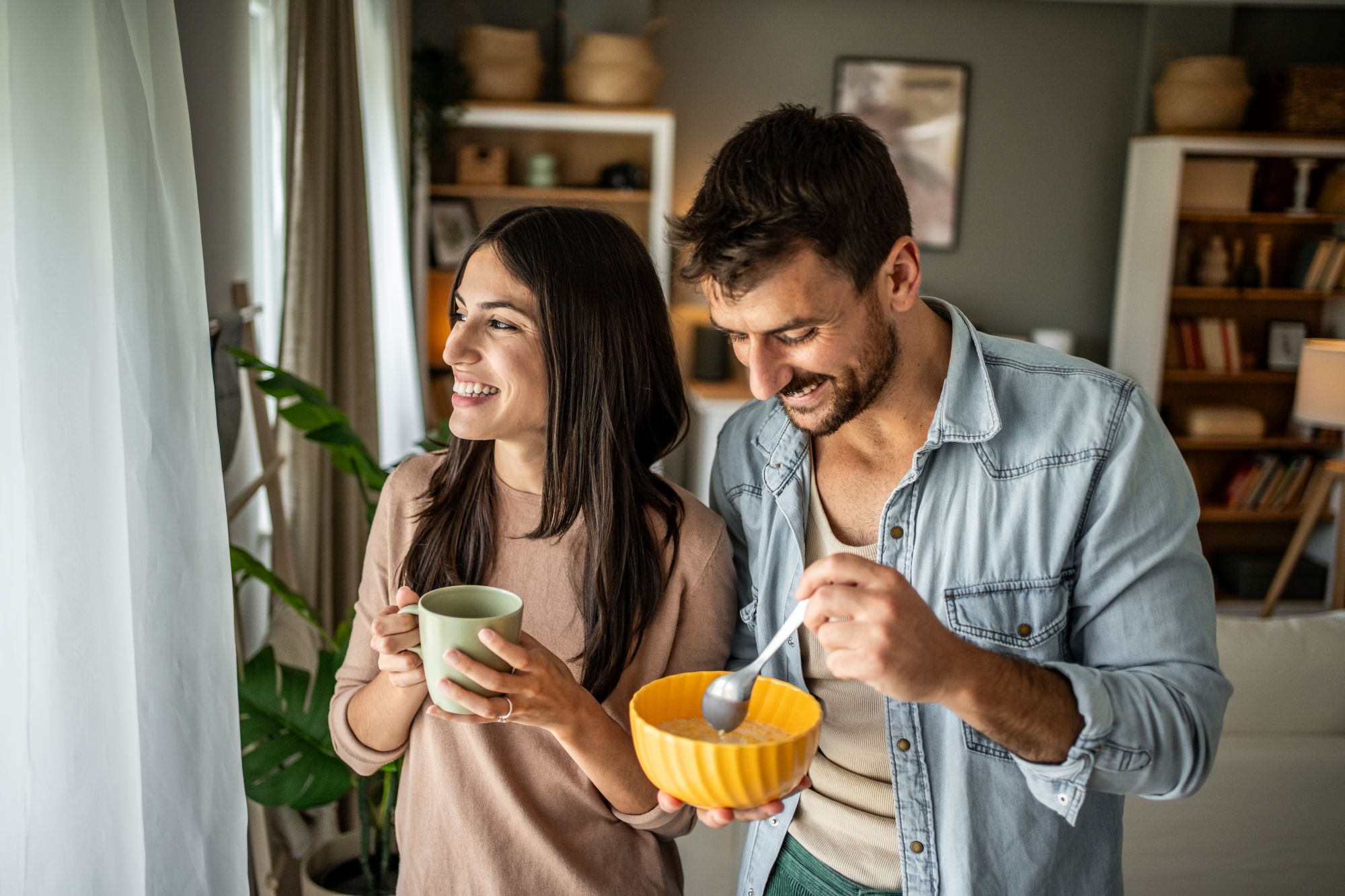 Couple eating breakfast and looking out window; ?>